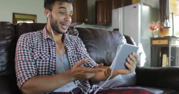 Człowiek zrobić Online wideo zawołać przy użyciu siedzieć na komputerze typu Tablet na trenera w salonie, Łacińska facet mówiąc Internet komunikacji - Materiał filmowy, wideo