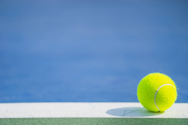 una nueva pelota de tenis en línea blanca en cancha dura azul y verde con luz de la derecha
 - Foto, Imagen