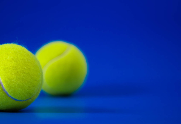 dwa nowe piłki tenisowe na niebieski sądu z światła z lewej, cień i kopiować miejsca na prawo - Zdjęcie, obraz