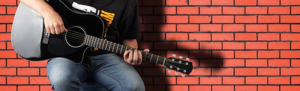 Μουσική - θραύσμα ανθρώπου παίζουν ένα μαύρο ακουστική κιθάρα - Φωτογραφία, εικόνα