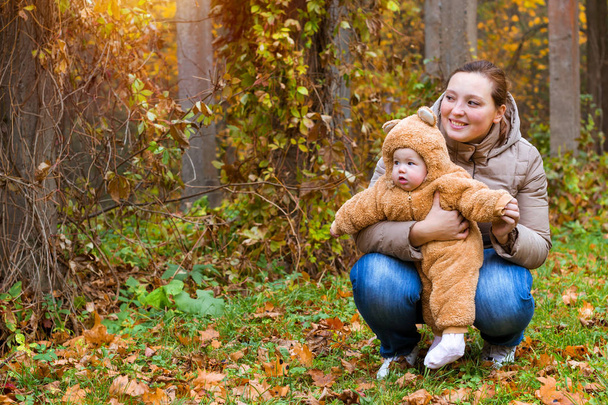 Woman with baby in arms, posing in autumn Park - Φωτογραφία, εικόνα