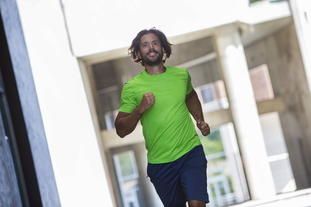 Sportovní mladý muž běží a cvičit ve městě - Fotografie, Obrázek