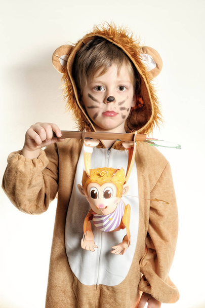 Хлопчик одягнений для лева з паперовою мавпою в руках
 - Фото, зображення