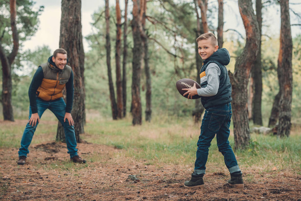 Отец и сын играют с мячом в лесу
 - Фото, изображение