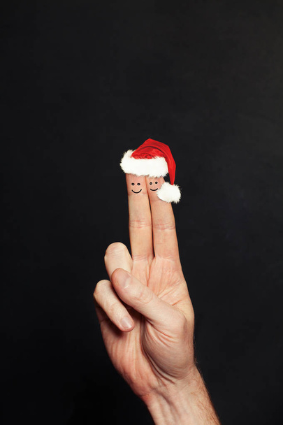 Kerst paar. Twee gelukkig kerstfeest gezicht vingers in Santa hoeden - Foto, afbeelding
