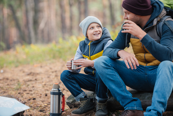 father and son drinking tea in forest - Foto, Bild