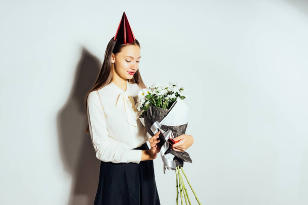 young beautiful girl celebrates something, in a red cap, holding a large bouquet of white flowers - Photo, image