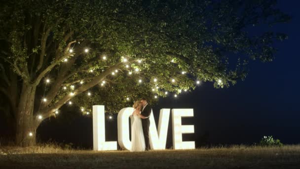 Mladý pár v lásce v večerní šaty se tančí poblíž světlo milostné dopisy. - Záběry, video