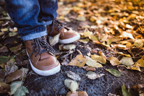 Closeup of toddler's boots on bright autumn leaves background. C - Φωτογραφία, εικόνα