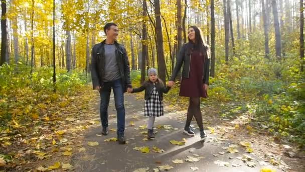 Familia feliz con una pequeña hija a pie en el parque de otoño
 - Imágenes, Vídeo