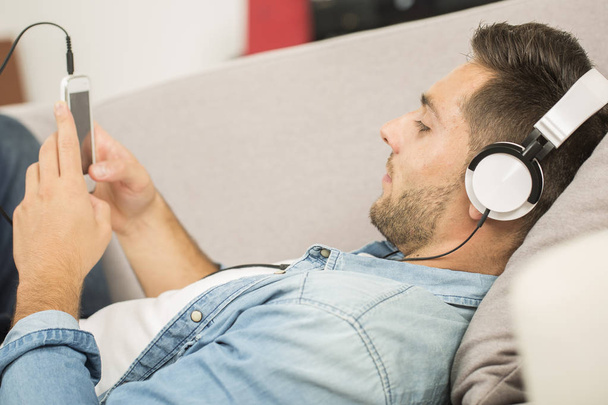 Cheerful man relaxing in sofa, listening to music - Foto, Imagen