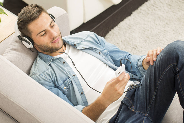 Cheerful man relaxing in sofa, listening to music - Valokuva, kuva