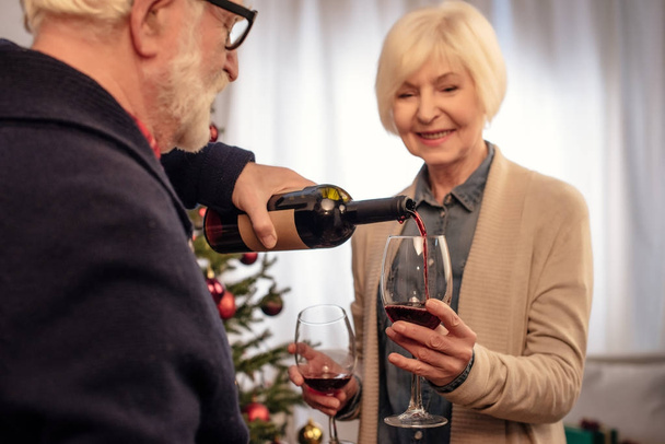 senior couple with wine at christmas - Фото, изображение