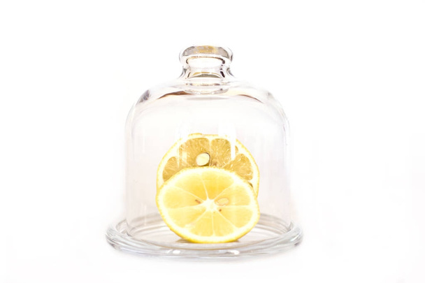 Sliced lemon on a saucer under a glass cap. Isolated - Zdjęcie, obraz
