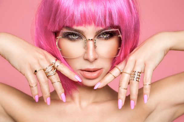 schönes Modell in rosa Perücke und farbigem Make-up mit langen farbigen Nägeln - Foto, Bild