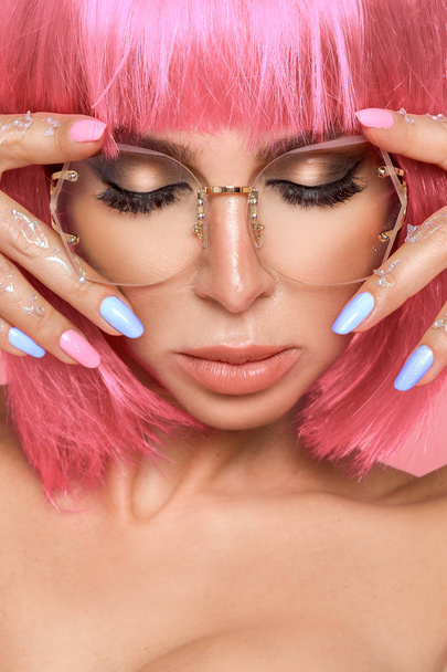 Mooi model in roze pruik en gekleurde make-up met lange gekleurde nagels - Foto, afbeelding