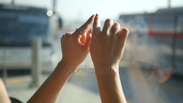 Kobiecych rąk narysować znak na okienku na lotnisku. Ramienia kobiety przedstawiają kształt serca z słoneczne niebo w tle. Slow motion z bliska - Materiał filmowy, wideo