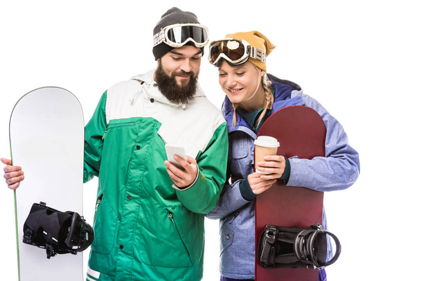 pareja con tablas de snowboard usando smartphone
 - Foto, imagen