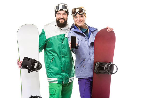 pareja con tablas de snowboard mostrando smartphone
 - Foto, imagen