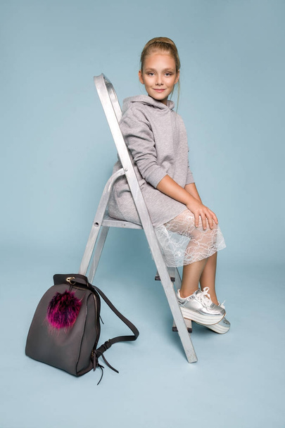 Roztomilá holčička v školní oblečení a školní batoh stojící na modrém pozadí - Fotografie, Obrázek