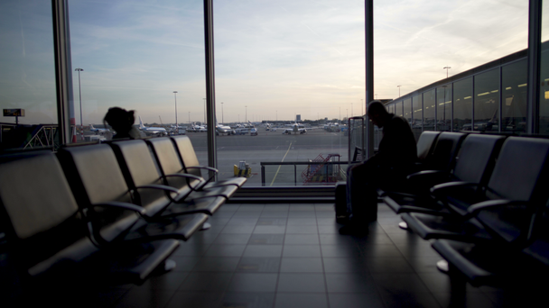 Samotny mężczyzna z walizką czeka na płaszczyźnie w hali odlotów, terminal - Materiał filmowy, wideo