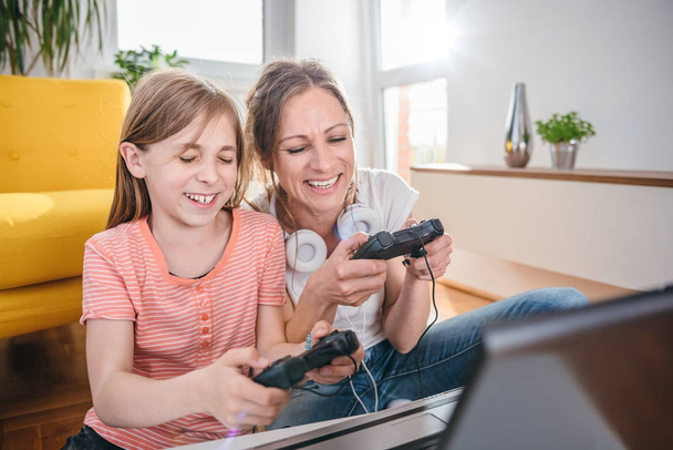 Mother and daughter playing video games on laptop at home - Φωτογραφία, εικόνα