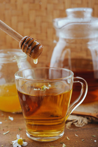 Ромашковый чай, мед и свежие цветы на деревенском деревянном столе
 - Фото, изображение
