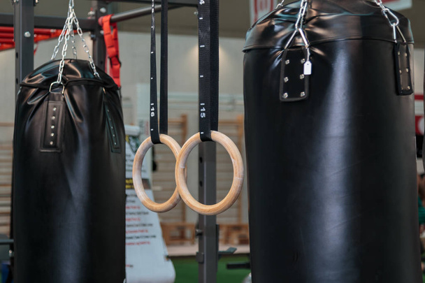 Black Punching Bag and Crossfit Fitness Rings: Workout Equipment - Photo, Image