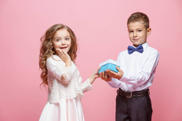 Boy and girl standing in studio on pink background - Foto, afbeelding