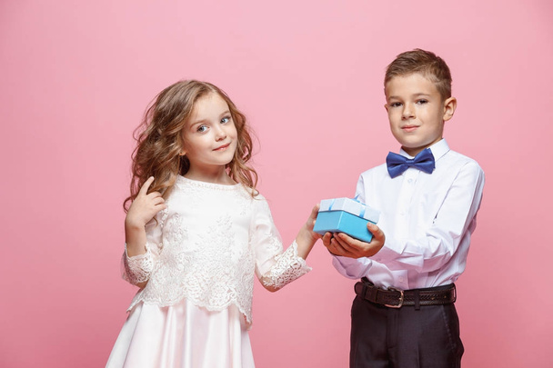 Boy and girl standing in studio on pink background - Фото, изображение