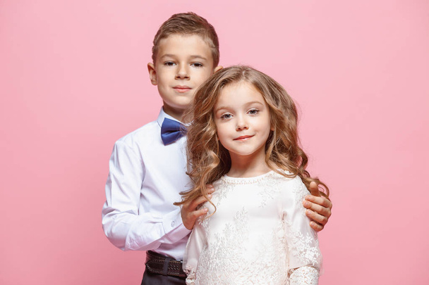 Boy and girl standing in studio on pink background - Photo, image
