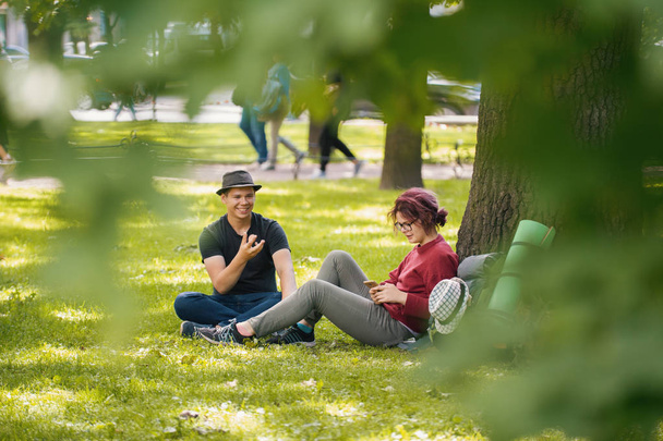 Jovem e mulher turistas com mochilas têm descanso no parque
 - Foto, Imagem