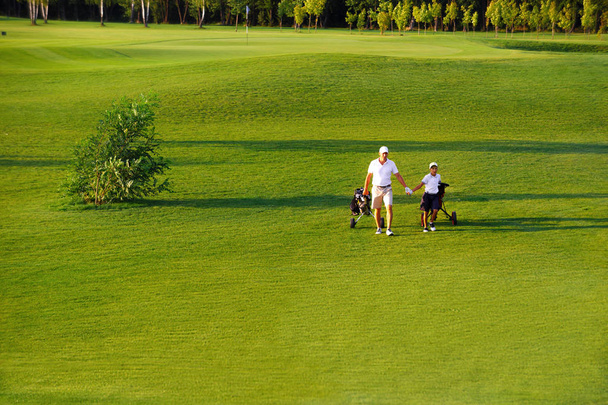 az ember a saját fia golfozó, séta a golfpálya - Fotó, kép