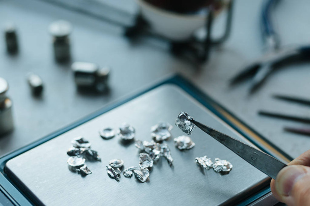 Jewelry tools. Jewellery. Goldsmith workplace, workspace on light background. Hand craft. Workshop. Manufacturing. Weigh-scales with granules of metal silver and platinum. Closeup. Toned - Photo, image