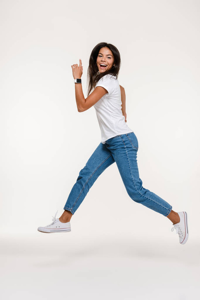 Full length portrait of a pretty happy woman jumping - Fotografie, Obrázek