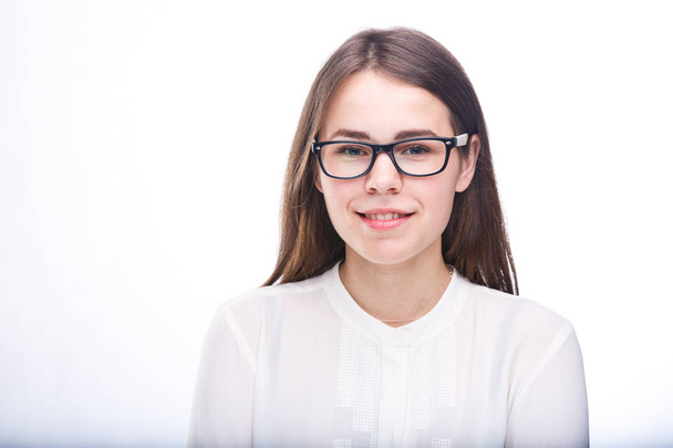 beautiful young girl in glasses with black frame, with brown hair over shoulders and white shirt on white isolated background. - Фото, изображение