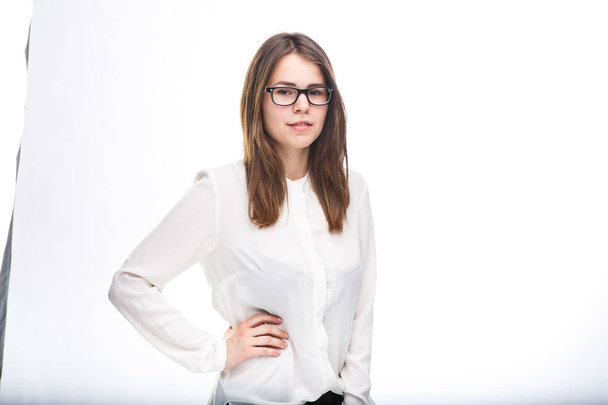 beautiful young girl in glasses with black frame, with brown hair over shoulders and white shirt on white isolated background. - Fotografie, Obrázek