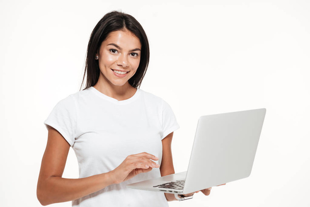 Portrait of a smiling brunette woman holding laptop computer - Foto, afbeelding