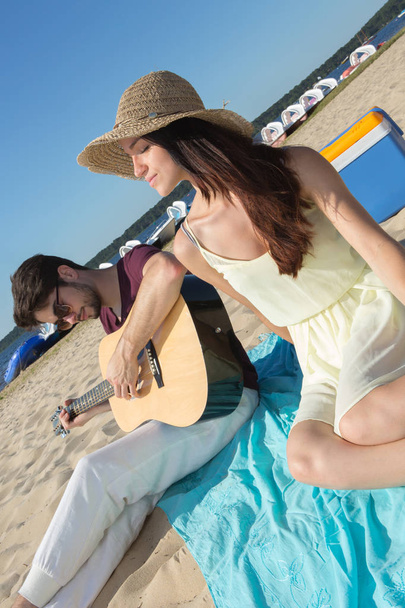 young man with his guitar and girlfriend on the beach - Foto, immagini