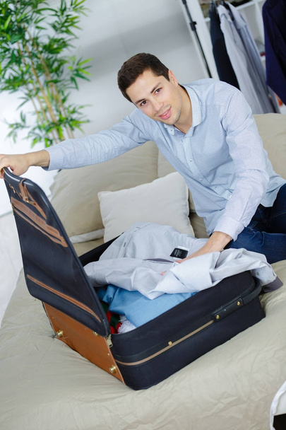 man putting shirt into a suitcase - Foto, afbeelding