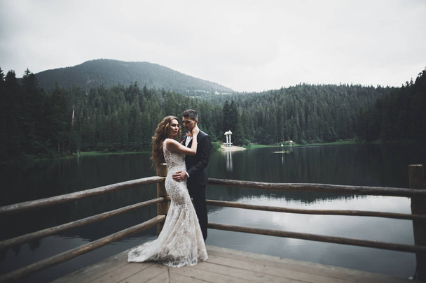 Happy wedding couple posing over beautiful landscape in the mountains - Fotoğraf, Görsel