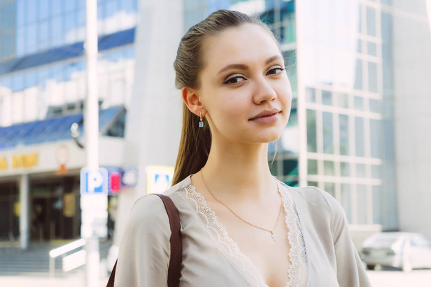 lovely pretty girl on a walk in the city stands on the background of a beautiful multi-storey building - Photo, Image