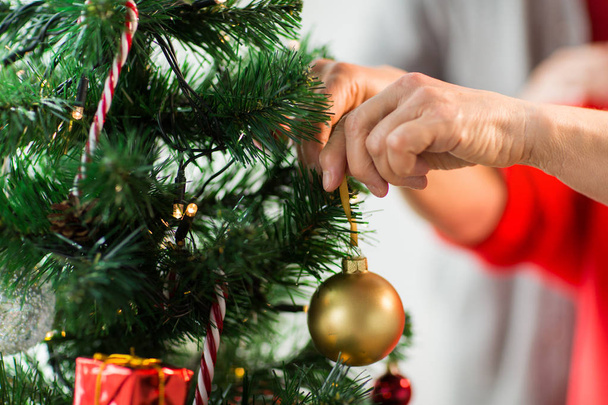 年配の女性がクリスマス ツリーを飾るをクローズ アップ - 写真・画像