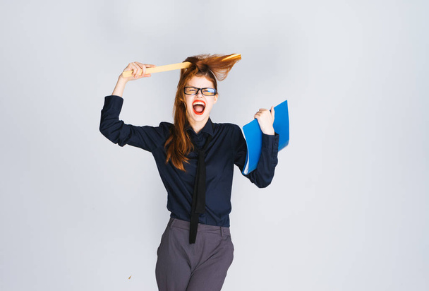 crazy redhead wrapped her hair around the ruler, holds a blue folder and laughs - Foto, afbeelding