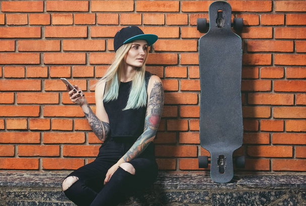 Beautiful, sexy hipster girl in tattoos against a red brick wall - Valokuva, kuva