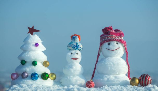 Snowmen with smiley faces in hats on winter day - Fotoğraf, Görsel