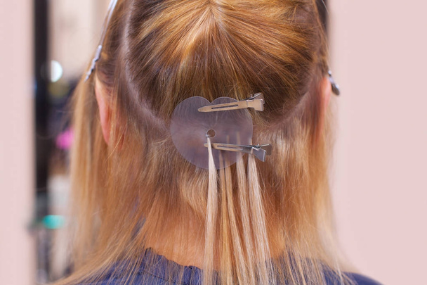 Le coiffeur fait des extensions de cheveux à une jeune fille, une blonde
 - Photo, image