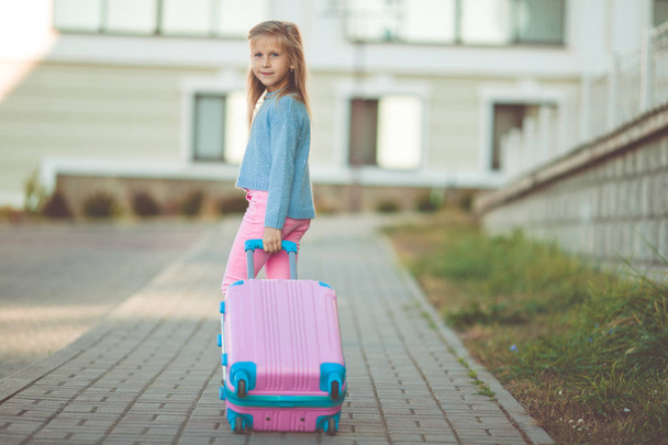 Happy little girl with pink suitcase is ready for vacations - Fotografie, Obrázek