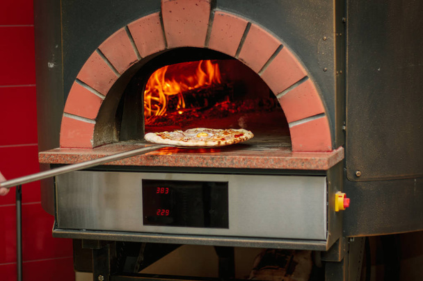 Pizza na pá em um forno de pizza tradicional
. - Foto, Imagem