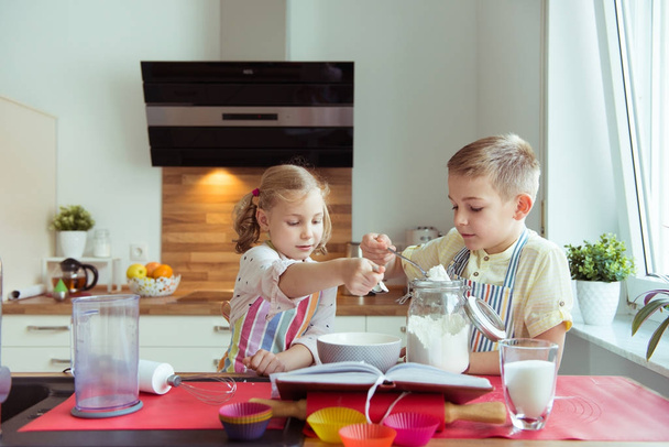 Two happy little and cute children preparing muffins in modern k - Photo, Image